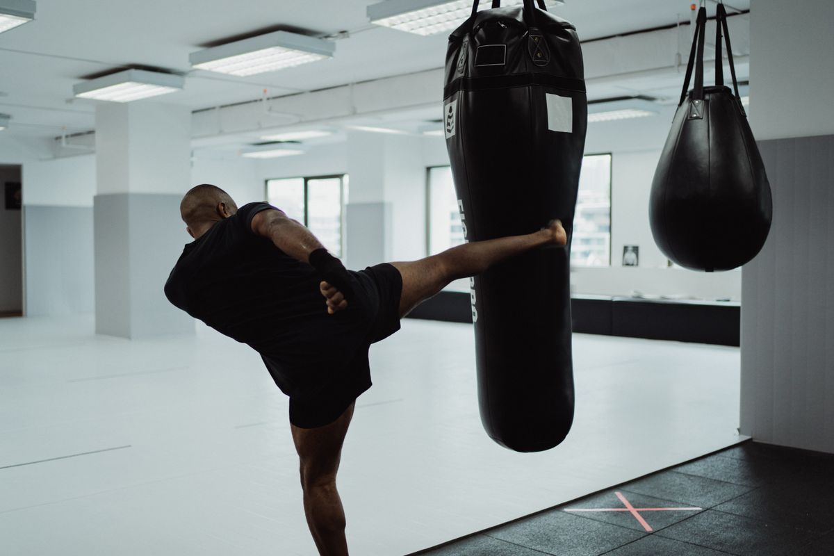An athlete landing a high kick on a heavy bag