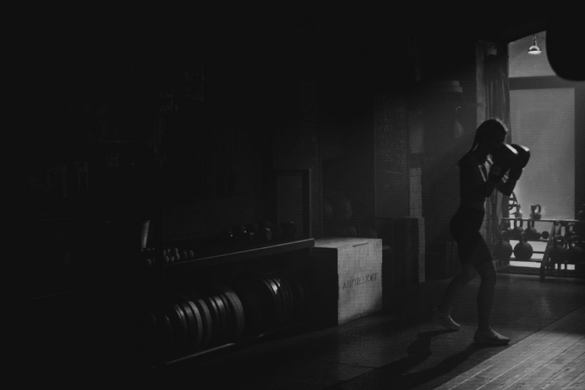 Silhouette of an athlete shadowboxing in a dark gym